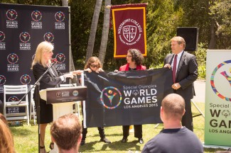 Joann Klonowski, Special Olympics world games, vice president of host town, presents the Special Olympics flag to Savannah Barclay, Special Olympics Southern California global messenger, Santa Barbara mayor Helene Schneider, and Westmont president Gayle D. Beebe (left to right).
