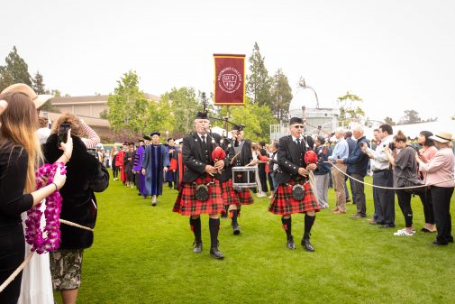 Bagpipers lead the graduates to Russell Carr Field