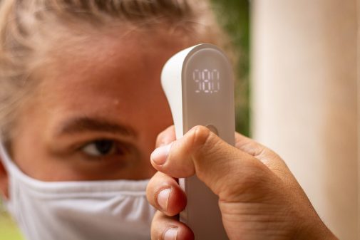 A student has her temperature taken before arriving on campus