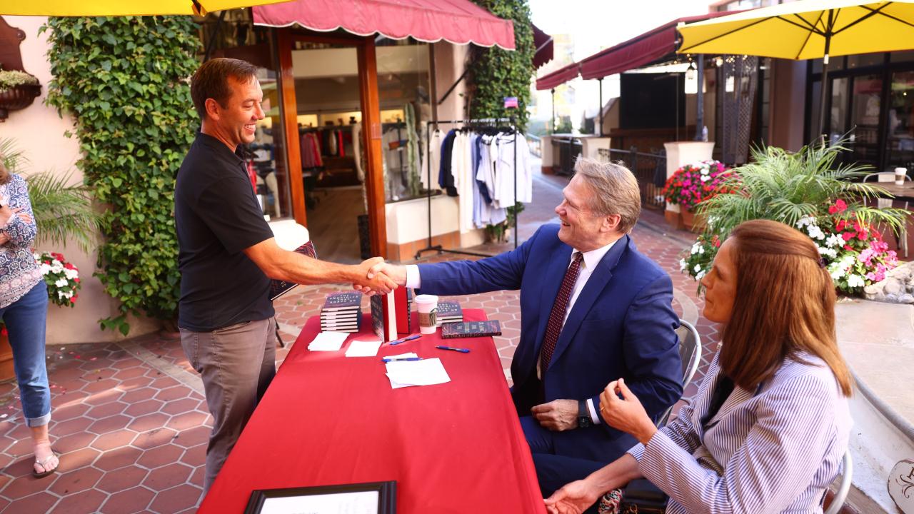 president beebe shaking hands with book signing guests