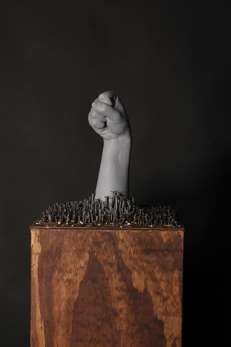 plaster hand and nails on wooden pedestal