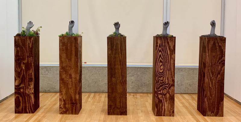 5 plaster hands surrounded by succulents and nails on wooden padestals