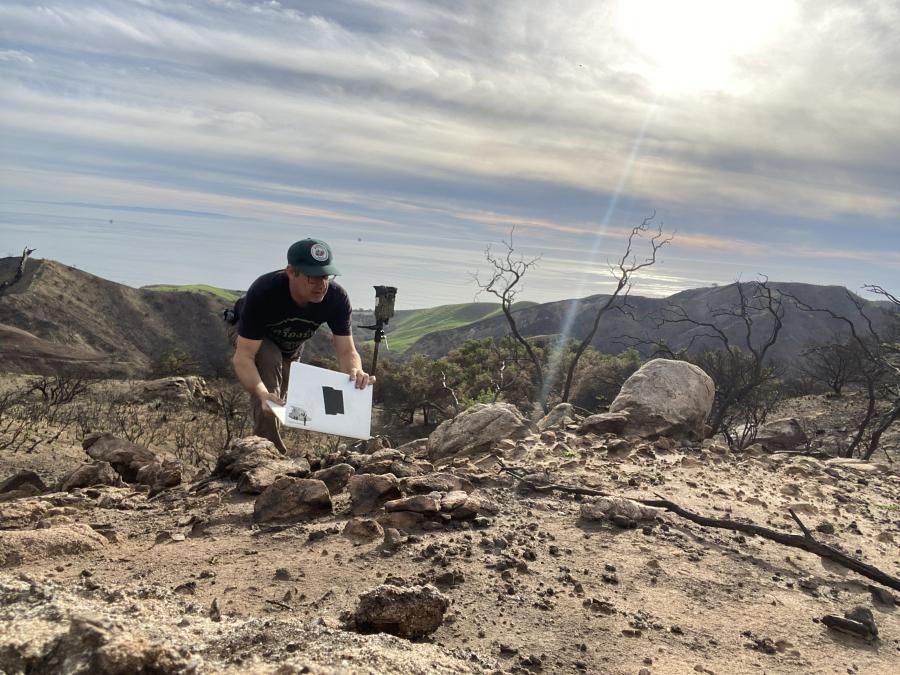 The artist setting up a special camera in a dry and burnt landscape.