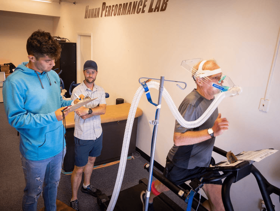 Man running on treadmill as students record his data.